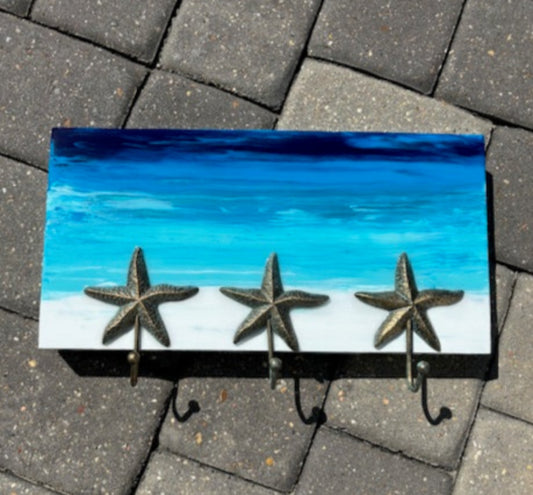<p>I painted this wood rack with a tranquil ocean scene and covered the entire piece with resin. <br>Three starfish hooks have a slight green patina.</p> <p>The perfect piece to hang your towels, hats or pet leashes.</p> <p>Approximate size: 16 inches long, 9 inches tall and 1.5 inches deep</p>
