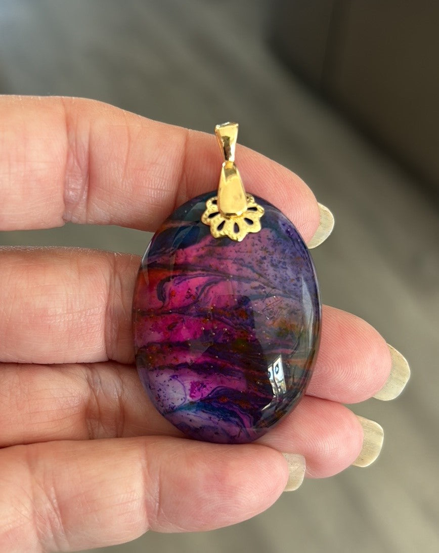 Truly, one of a kind pendant.
Pink and purple’s with touches of blue and orange make up this beautiful cabochon.
Handcrafted out of resin
Cabochon has a gold tone accent and bail
Lightweight
Approximate size including bale 2 inches