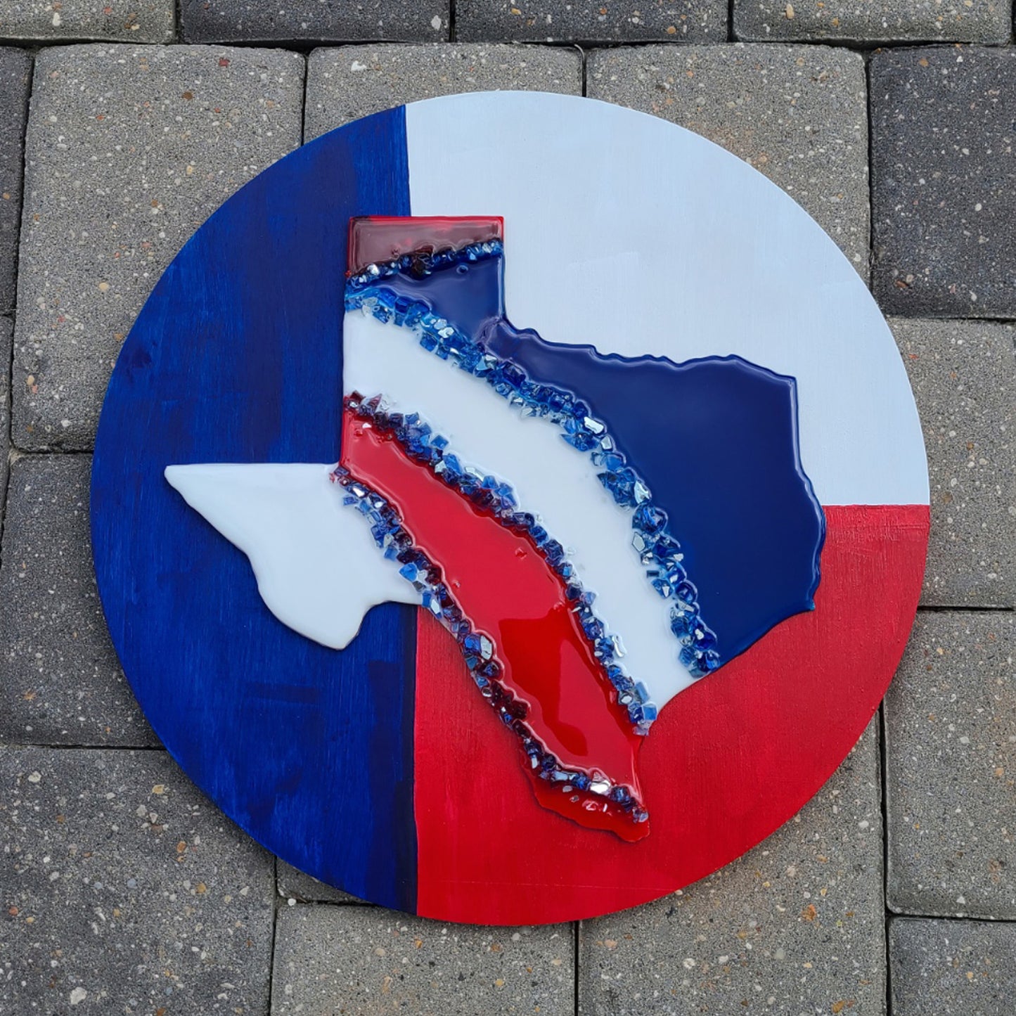 I guess I will always be a Texan at heart. I had so much fun creating this piece. I created this shape of Texas with acrylic paints, crushed glass and resin on a laser cut shape and mounted it on a wood cradle board. Round wood is pine. Resin is UV resistant. Approximate measurements: 15.25 inches round; .5 inches thick. Ready to hang using the inside of the cradle board.