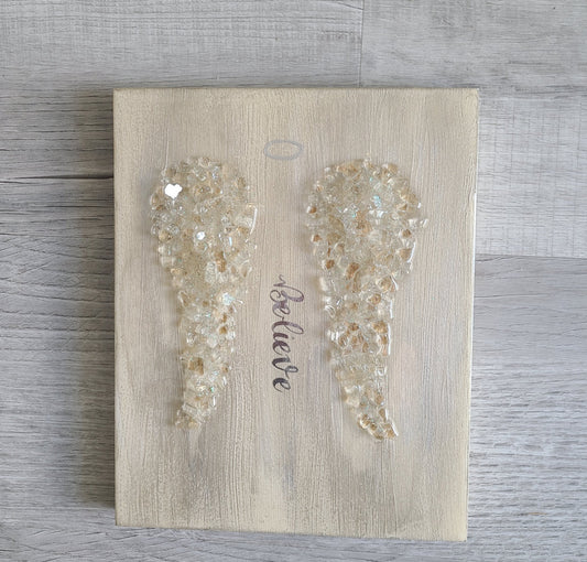 Believe in Angels? I do! The wood is painted in distressed colors. Neutral colors will match any decor! I added crushed glass to create the angel wings. I painted a halo to complete the look. Beiges, Wilder and gold with iridescent glitter on the wings. Approximate size: 10 x 8 x .75 inches