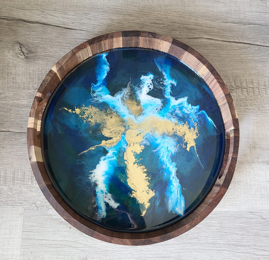 Striking cobalt blue and teal under a white and gold electric splash. Handcrafted Multi-tone wood tray has cut-out handles for easy carrying. Tray is not too heavy. Suitable for serving drinks or food, as a catch-all for remotes or make a beautiful statement alone. Resin is UV and Heat Resistant. Round tray is approximately 14 inches in diameter and 2 inches tall.