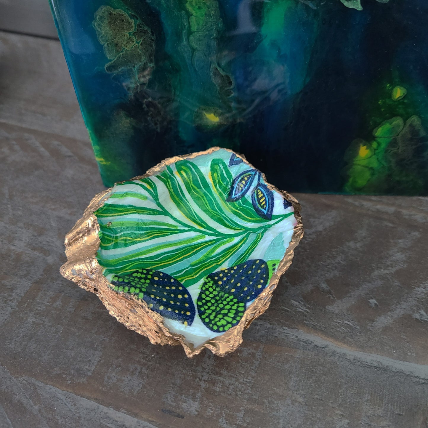 I used the Decoupage method to decorate this oyster shell and created this trinket dish. Bright green and navy blue heart and leaves are surrounded by gold trim. Use alone or to hold a few of your favorite things. A minimum of 3 layers of varnish has been used to protect this piece. I hand painted the little beads that I attached to the bottom of the shell. Truly a one-of-a-kind piece! Rings NOT included. Approximate size: 3.5 x 3.25 inches at the widest parts.