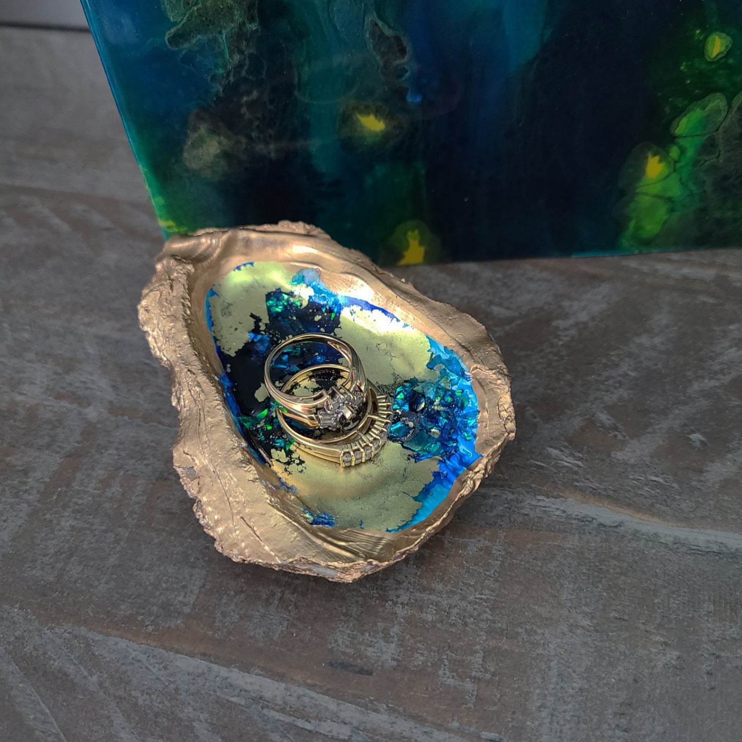 I poured resin in this oyster shell and added alcohol inks and iridescent paper to create this little trinket dish or accent piece. This piece has a lot of texture and some sparkle too! I trimmed this piece in liquid gold. Approximate size: 3.5 x 2.5 inches at the widest parts. Rings are NOT included.