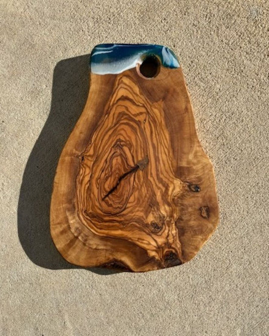 This beautiful board was made in Italy out of olive wood. I created a small bit of resin ocean on it. Most of the beautiful wood is visible.
Live edge on all sides.
Hole for hanging
Approximate size: 10 x 7.25 x 1 inches (at the widest point)