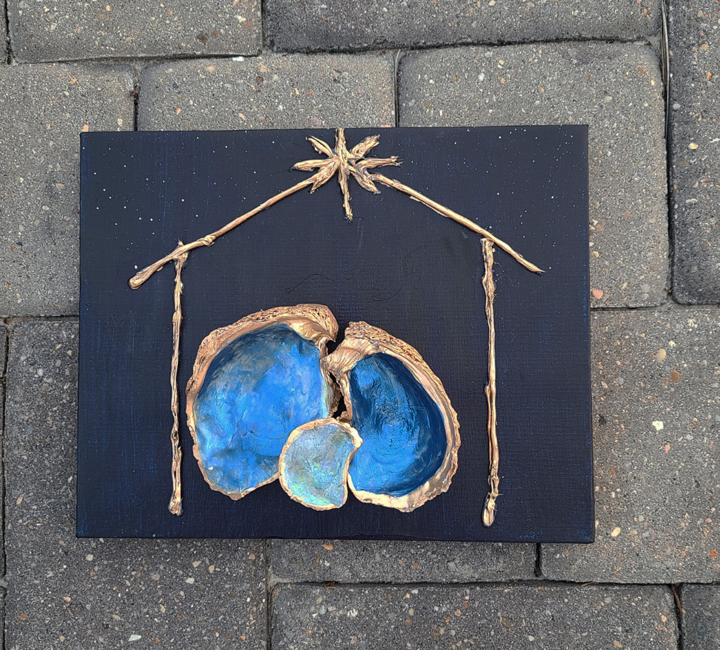 I love the way the oyster shells nestle together. The shells are painted with an iridescent coat and then sprayed with acrylic sealer. The edges are trimmed in Gold. The Manager is painted gold. It is a stark contrast to the dark night full of stars. Approximate size: 8 x 10 x 1 inches