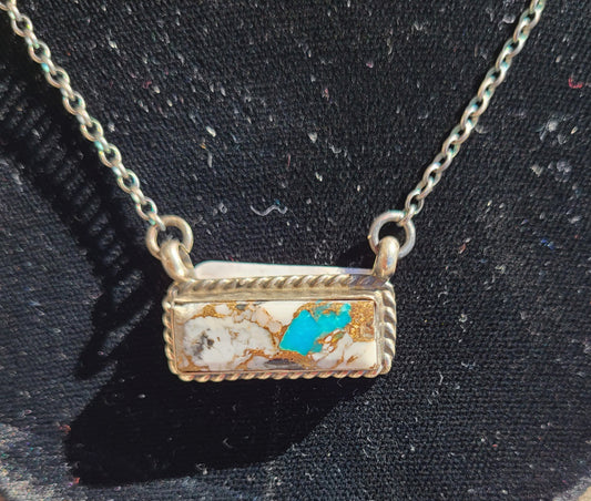 Beautiful colors in this White Buffalo and Turquoise necklace. Lots of gold matrix especially near the blue turquoise. Set in Sterling Silver bezel with twisted rope design. Chain is Sterling Silver. Oxidized for a vintage look. Navajo Artist, Augustine Largo Approximate length: 16 inch Bar is approximately 1 inch long Certificate of Authenticity as shown.