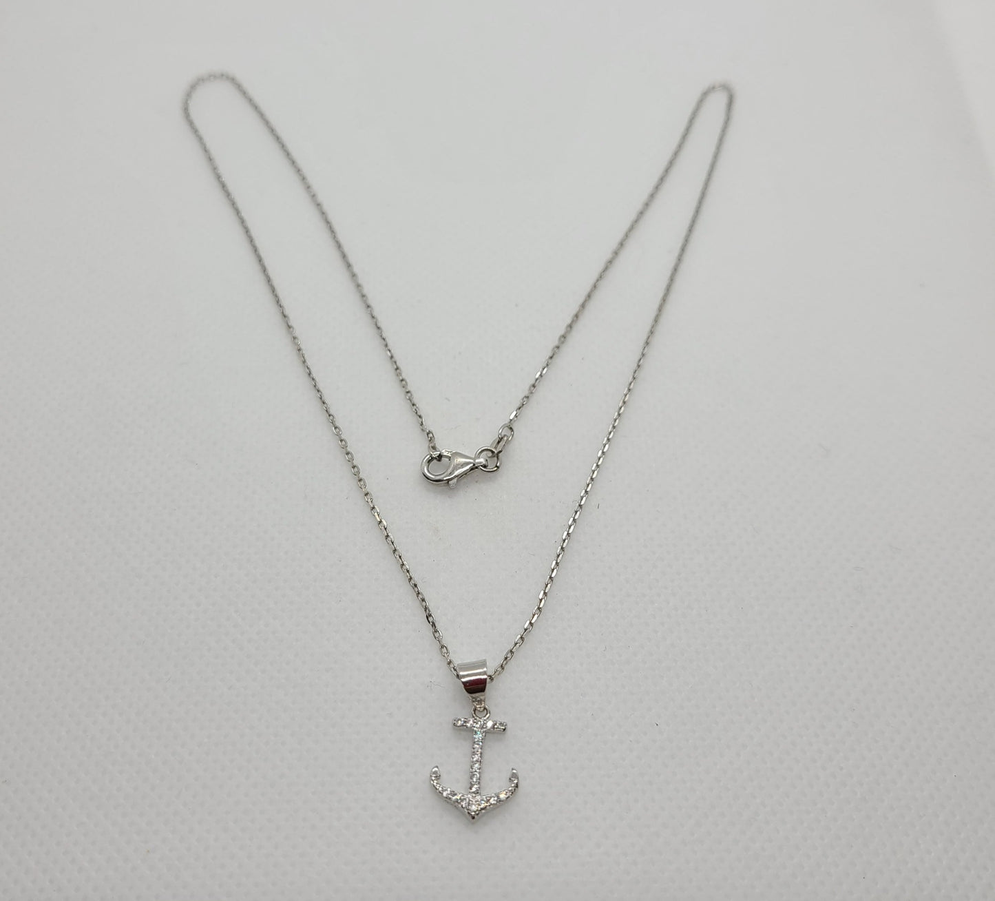 Beautiful anchor necklace is Sterling Silver with CZs. Both anchor and chain are Sterling Silver with Rhodium plating. Never needs polishing. Chain is approximately 18 inches long Nisha Design MSRP: $45
