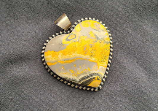 Very rare Bumblebee Jasper Stone. Heart Shaped Pendant. Vibrant yellow, orange gray and black. Brushed silver setting. Bead wire outlines the heart. Large bail for most any size necklace or leather. Navajo artist, Eli Skeets.