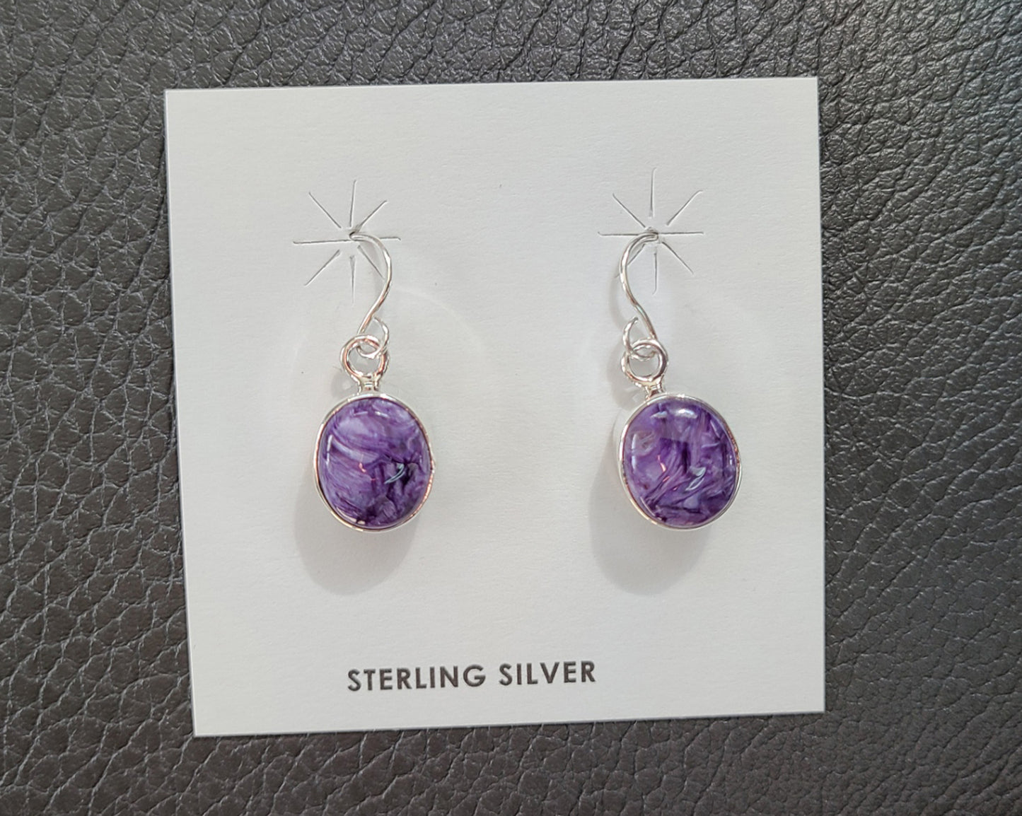 Oval Charoite stones set in simple Sterling Silver setting. Stones are various shades of light and dark purple. Sterling French Hooks. Overall length is approximately 1 inch. Made by Navajo artist, Juanita Long