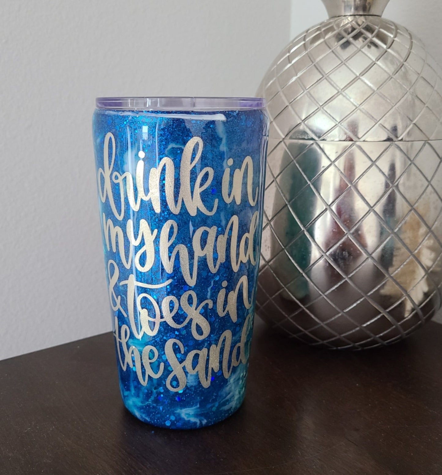 Tumblers are a challenge to make, especially on a vertical design. But I love how this one turned out. Drink in my hand & toes in the sand. Two layers of resin over the decal ensure that it will not come off. Various colors of the ocean sparkle through as the white waves of the ocean breaks onto the sand. 20 oz. Double Wall Stainless Steel under the resin. Comes with lid, straw and cleaner. Hand Wash only in warm water. DO NOT put in the dishwasher.