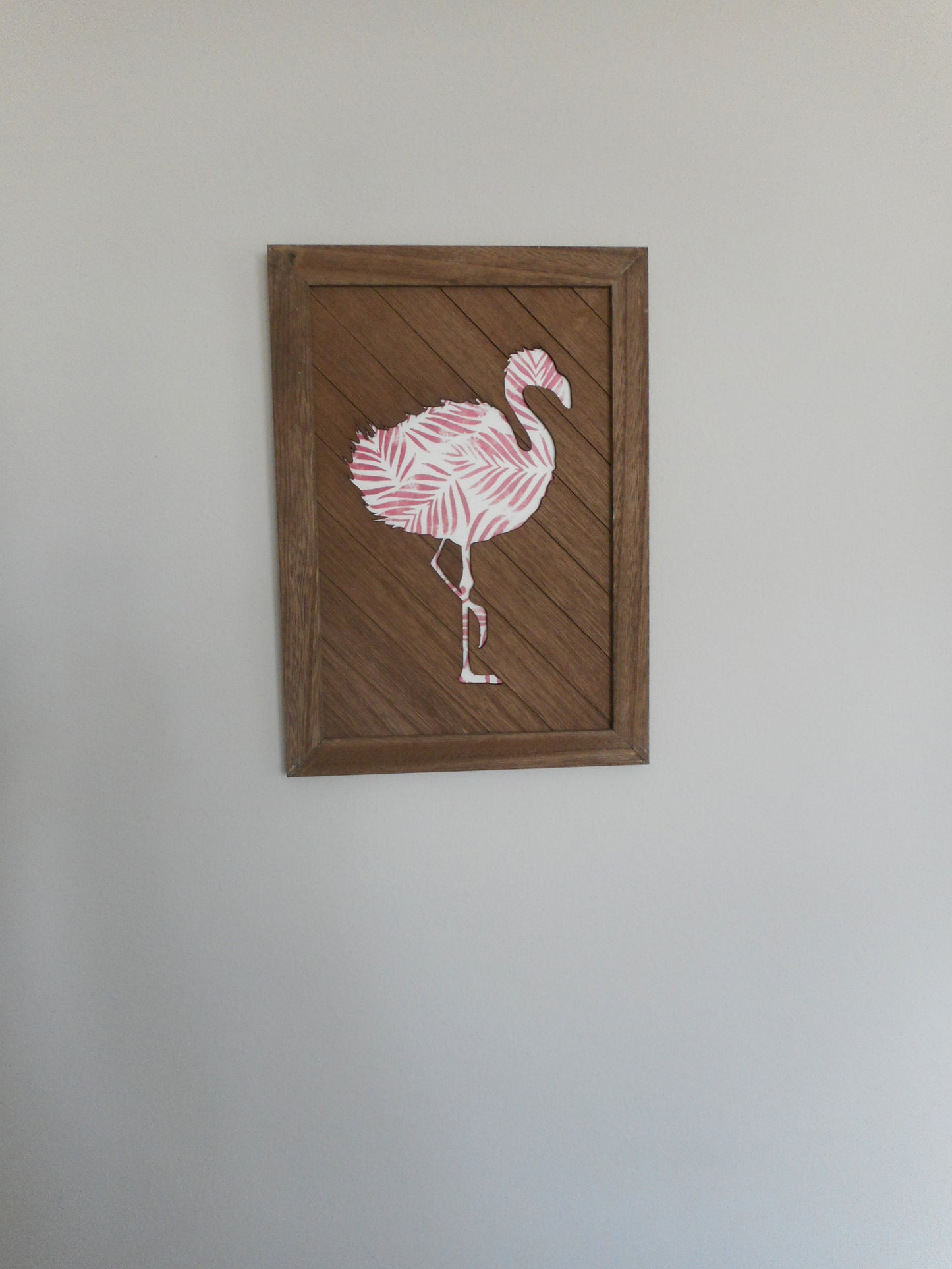 14 x 10 inches, Wood frame and diagonal wood with a cut out of a flamingo. Underneath is a pink and white print of palm leaves.
