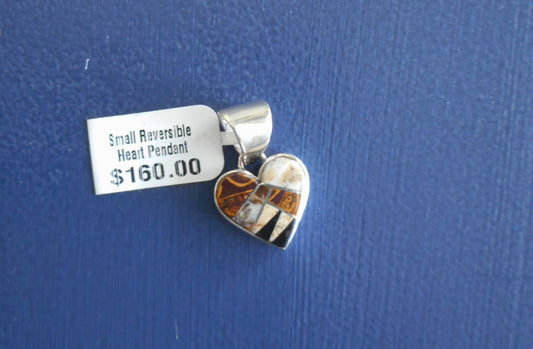 Small reversible heart pendant is inlaid with tiger's eye, picture jasper and onyx. Small pieces of sterling silver separate the stones. Reverse side is a sterling silver pueblo scene. Overall size is one inch.