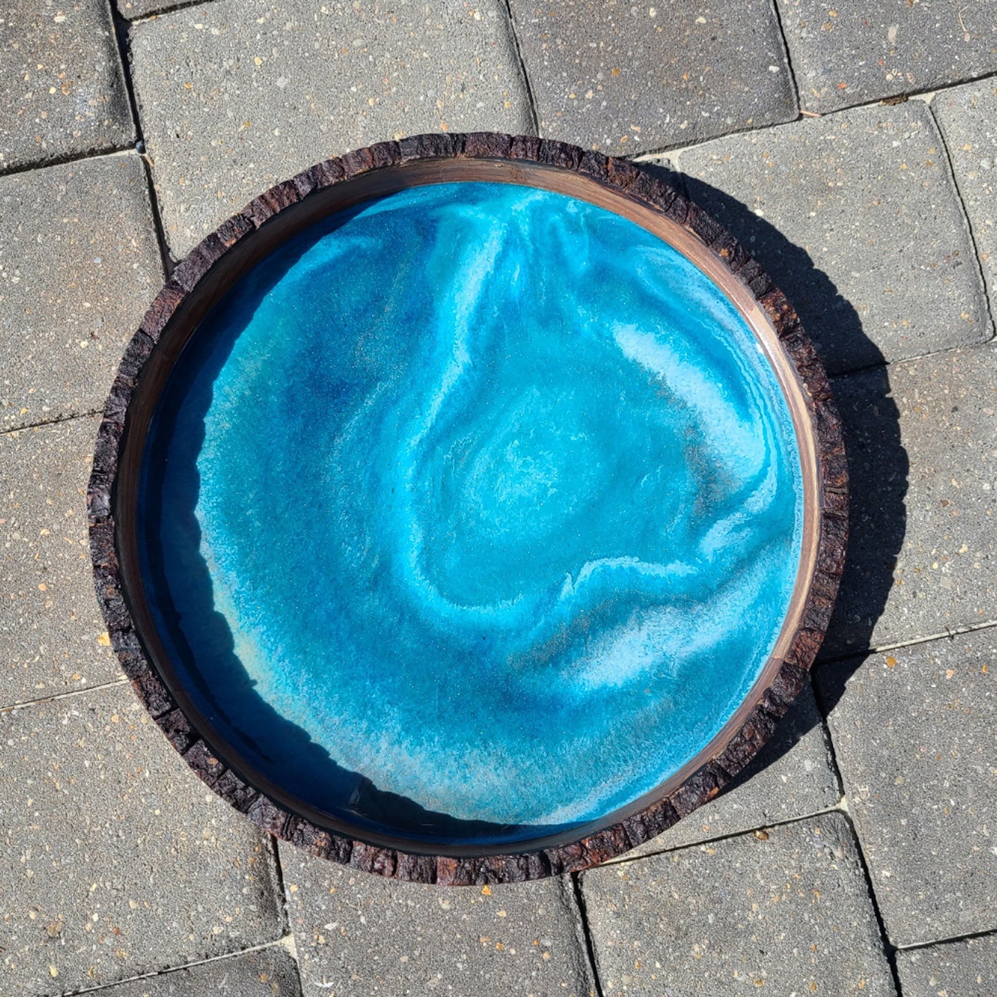 This tray is a little more subtle than I usually do. The rings of water look like you're looking into a deep hole. Round Wood tray with bark edge Resin is food safe and UV Resistant Approximate size: 14 x 2 inches Care: Wipe with a clean damp cloth. Wood can be conditioned with Food Grade Mineral Oil or Olive Oil.