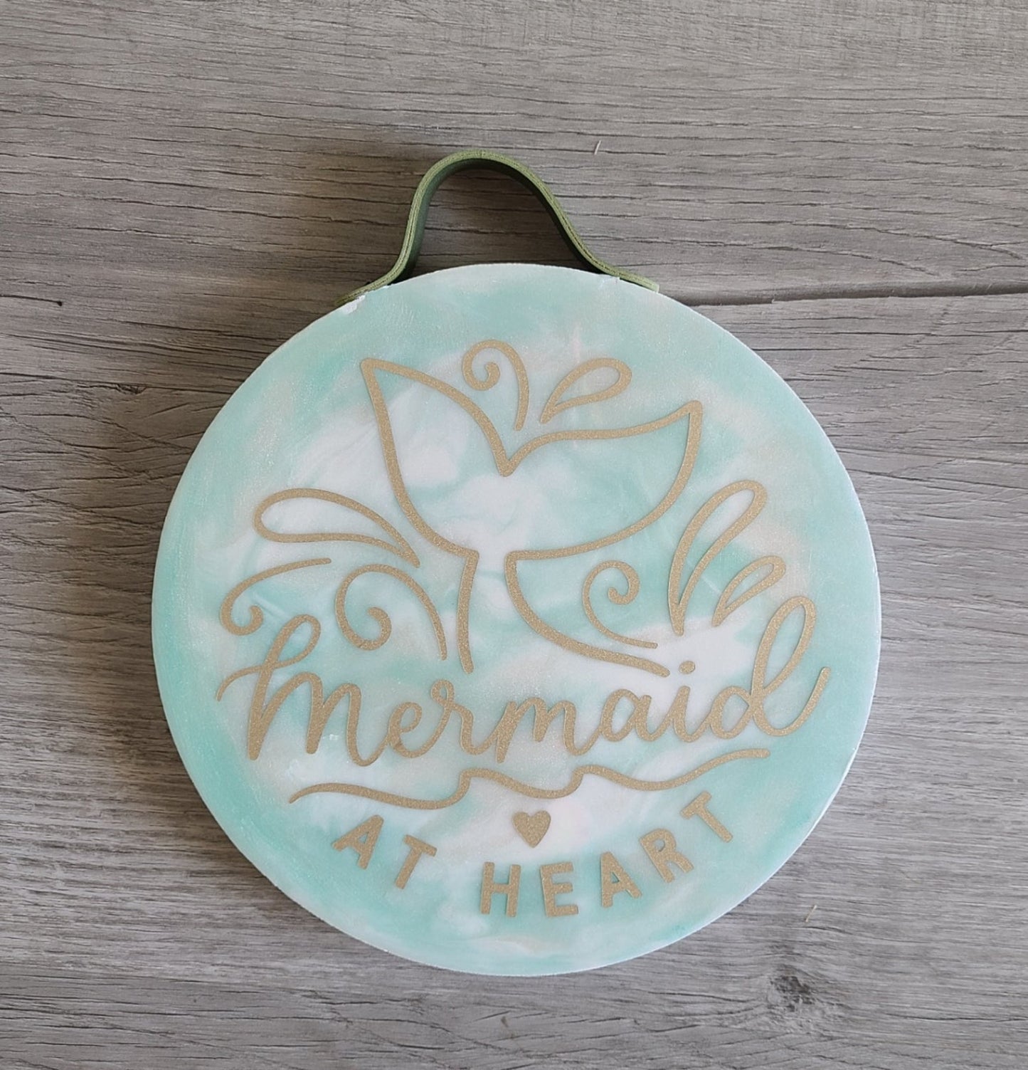 So cute! For every Mermaid at Heart. Mermaid tail with splashes. Wood Round With Resin in seafoam green, gold and white background and gold lettering. Sage Green Leather hanger. Approximate size: 8 inch x 1 inch