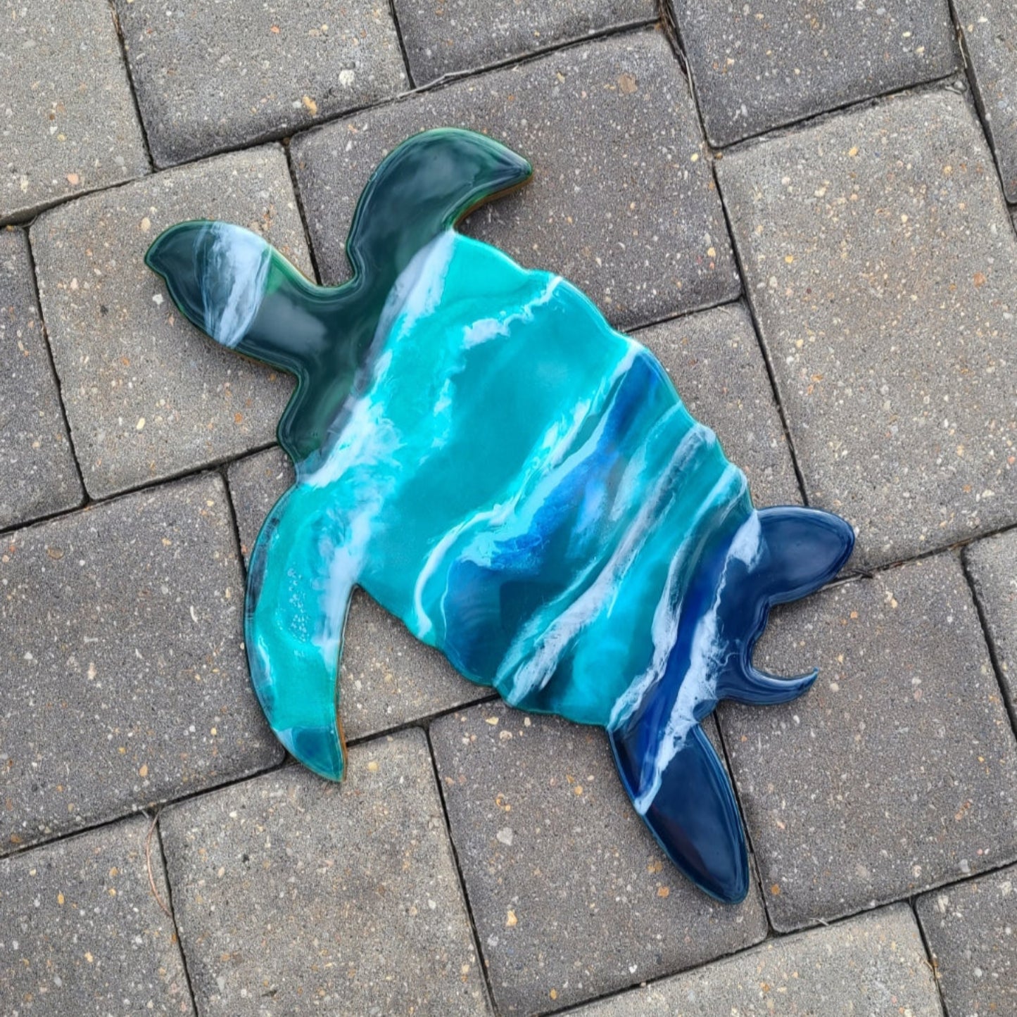 Adorable turtle is making his way through the waves. MDF Board is done in resin using UV Resistant Resin. Blues and greens with foamy white ocean waves. Saw tooth hanger on back is angled so he hangs as shown on the wall. Approximate size: 16 x 11.5 inches