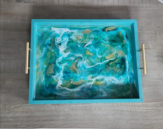 So stunning! Multiple layers of resin give lots of depth to this tray. Iridescent turquoise holographic film is layered with swirls of turquoise, white and gold. The tray is a lightweight wood (MDF) and has matt gold handles for carrying. Approximate size: 12 x 9 x 1.5 Inches Care: Wipe with a clean damp cloth or alcohol wipe. NOT for microwave or dishwasher.