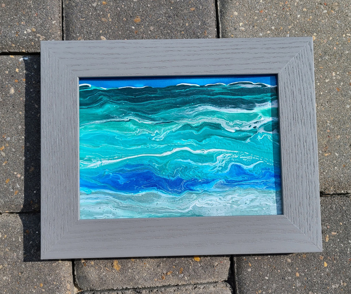 I created this lively, vivid ocean at my home in Florida after a storm came through and the ocean was active. The painting is made with Acrylic paints in shades of blue, green, white and gray. The painting is 5 x 7, but with the frame, it is 9x7. The frame is gray. Can hang on the wall or stand alone. It is signed on the back, but you can't see it unless you take it out of the frame.