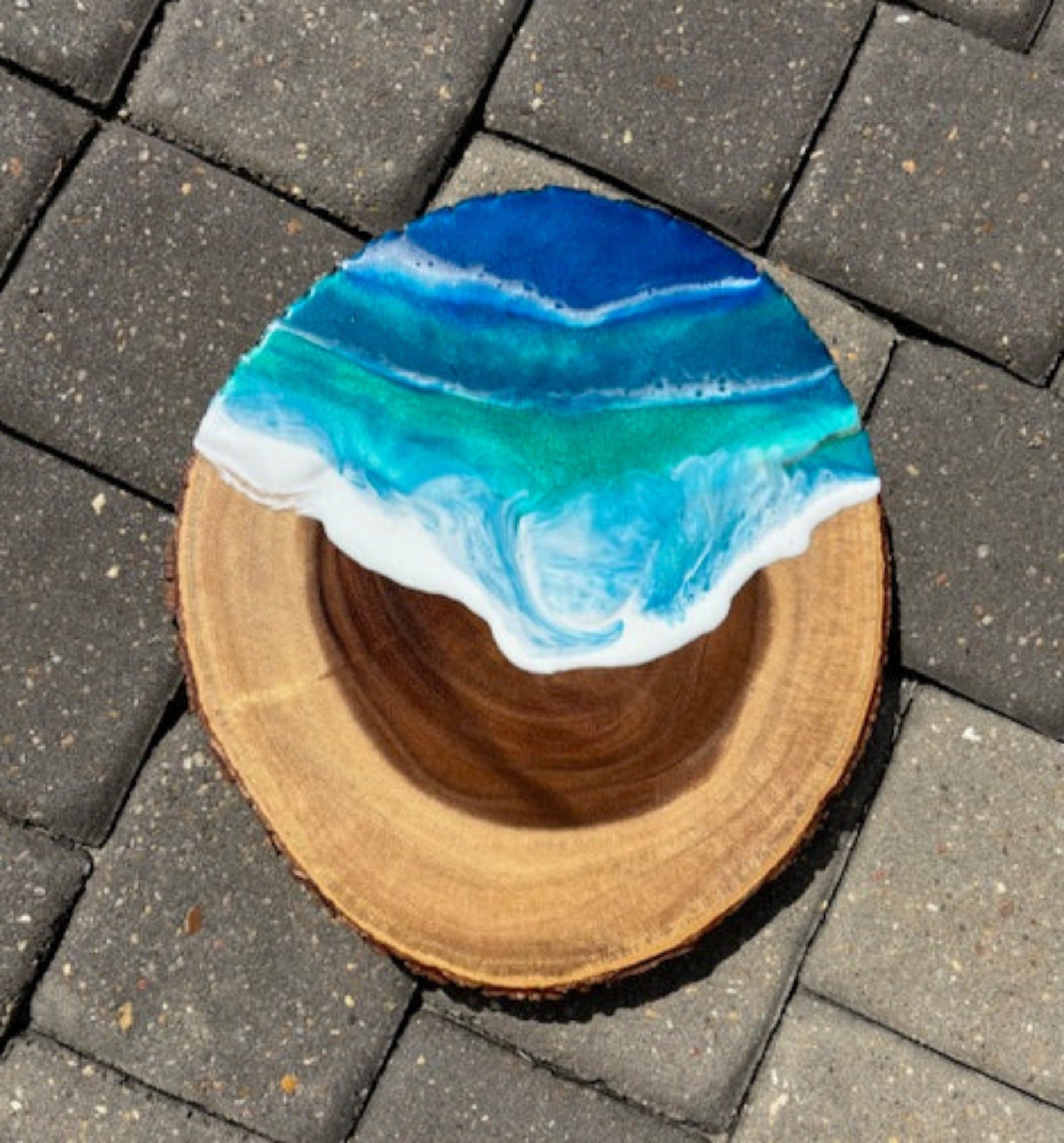 <p>Wood slice has bark all the way around. Use for charcuterie board, serving tray or display.</p> <p>Sparkling blue and green dance in foamy white waves of resin.</p> <p>Resin is food safe and heat resistant.</p> <p>Approximate size: 12.75 x 11x 1 inches</p>