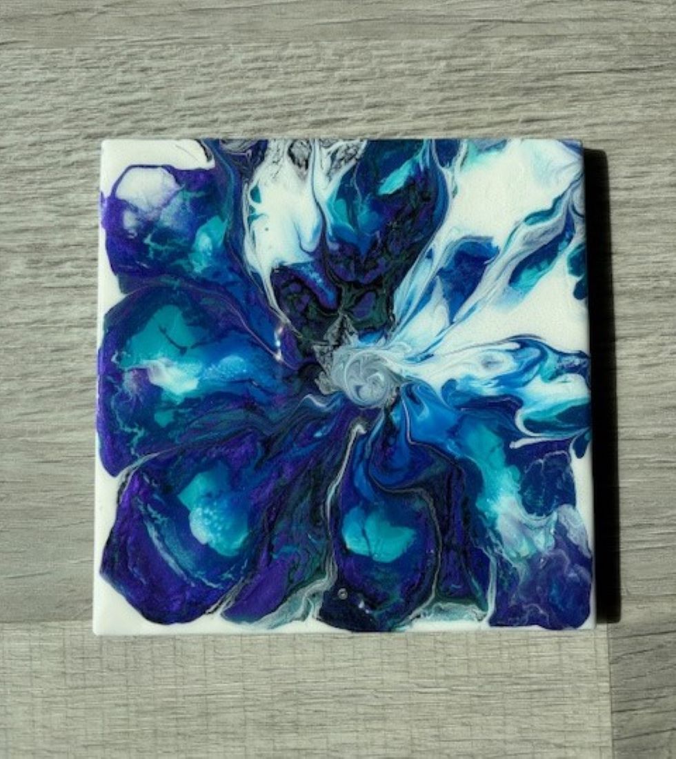 This is a dramatic flower bloom in blues, purple, black and white.

Artwork is done on tile and acrylic with two coats of resin. Can be used as a trivet or displayed an easel.

UV Resistant and Heat Resistant Resin. Food Safe too.

Cork backing to protect countertops or furniture.

Approximate measurements: 6 x 6 inches

Clean with a clean damp cloth