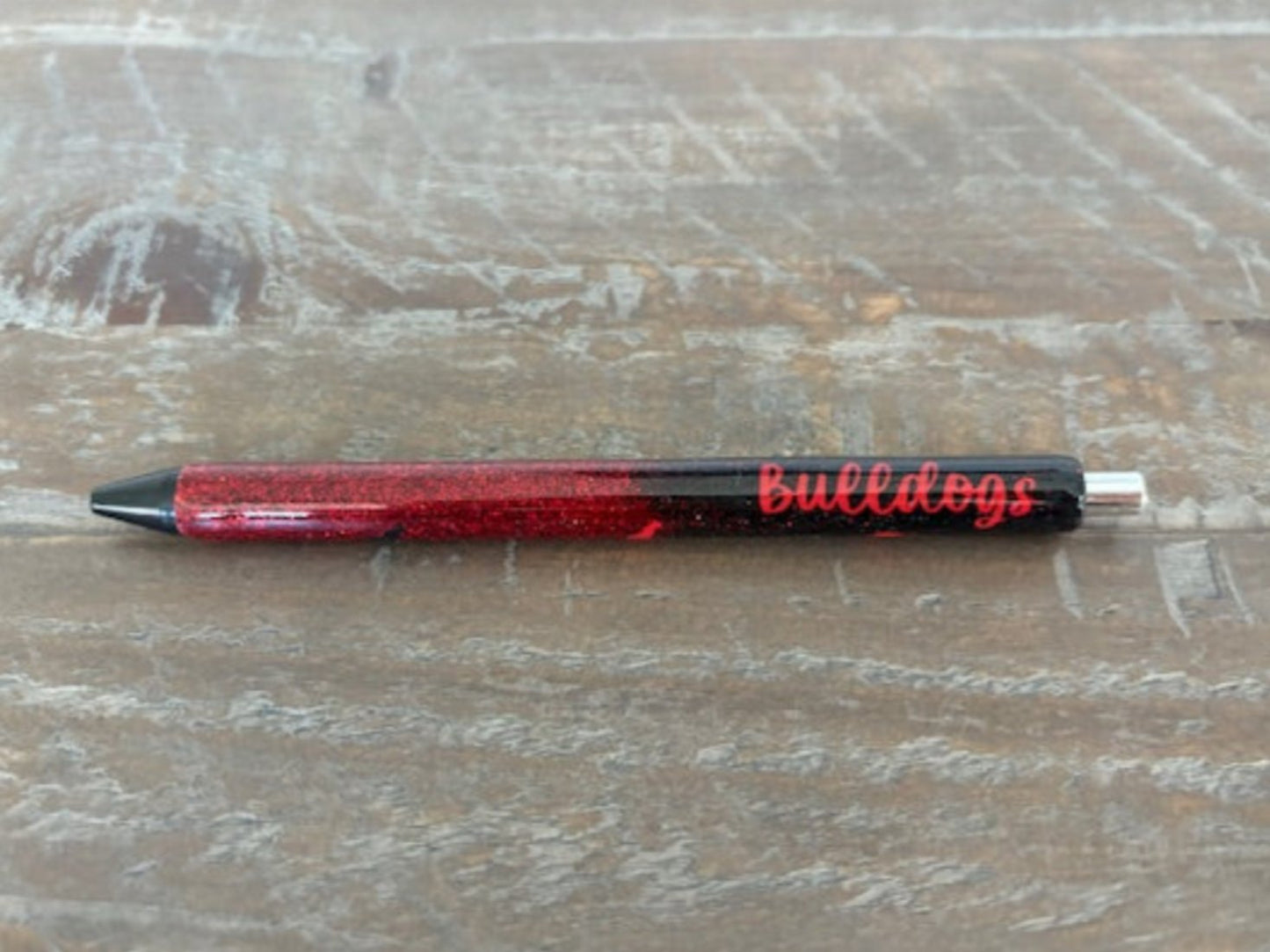 Are you a Bulldogs fan? This beautiful black and red pen sparkles beneath the word bulldogs and Bulldogs silhouettes.
Pen is refillable. Black gel ink. 
3 coats of epoxy will protect your dog!
The tip of the pen has red wax to protect it. It is easily removed with your fingernail for use.