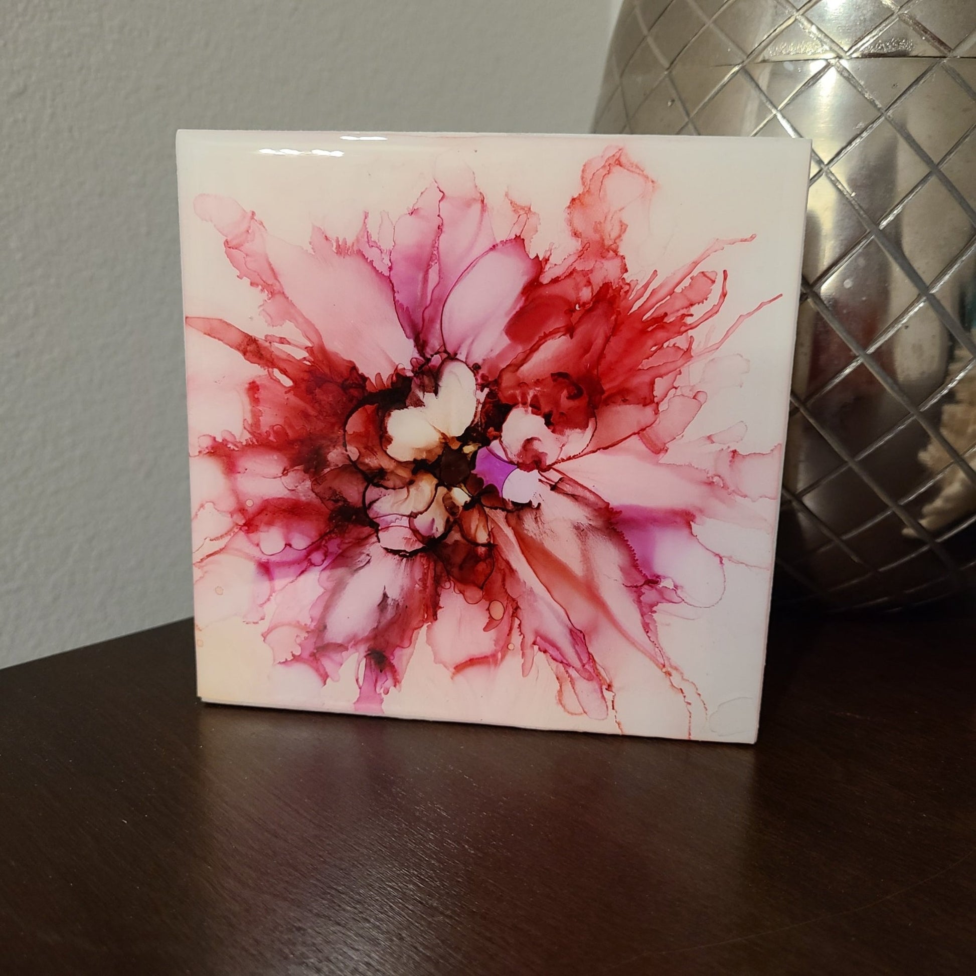 This little flower is done in pink and purple alcohol ink and then glued onto a wood board and coated with UV resistant resin.  Looks like a spider lily.  The artwork was protected with several coats of varnish and UV resistant coatings.  Can easily sit on a shelf or be hung.  Approximate size: 5 x 5 x .75 inches