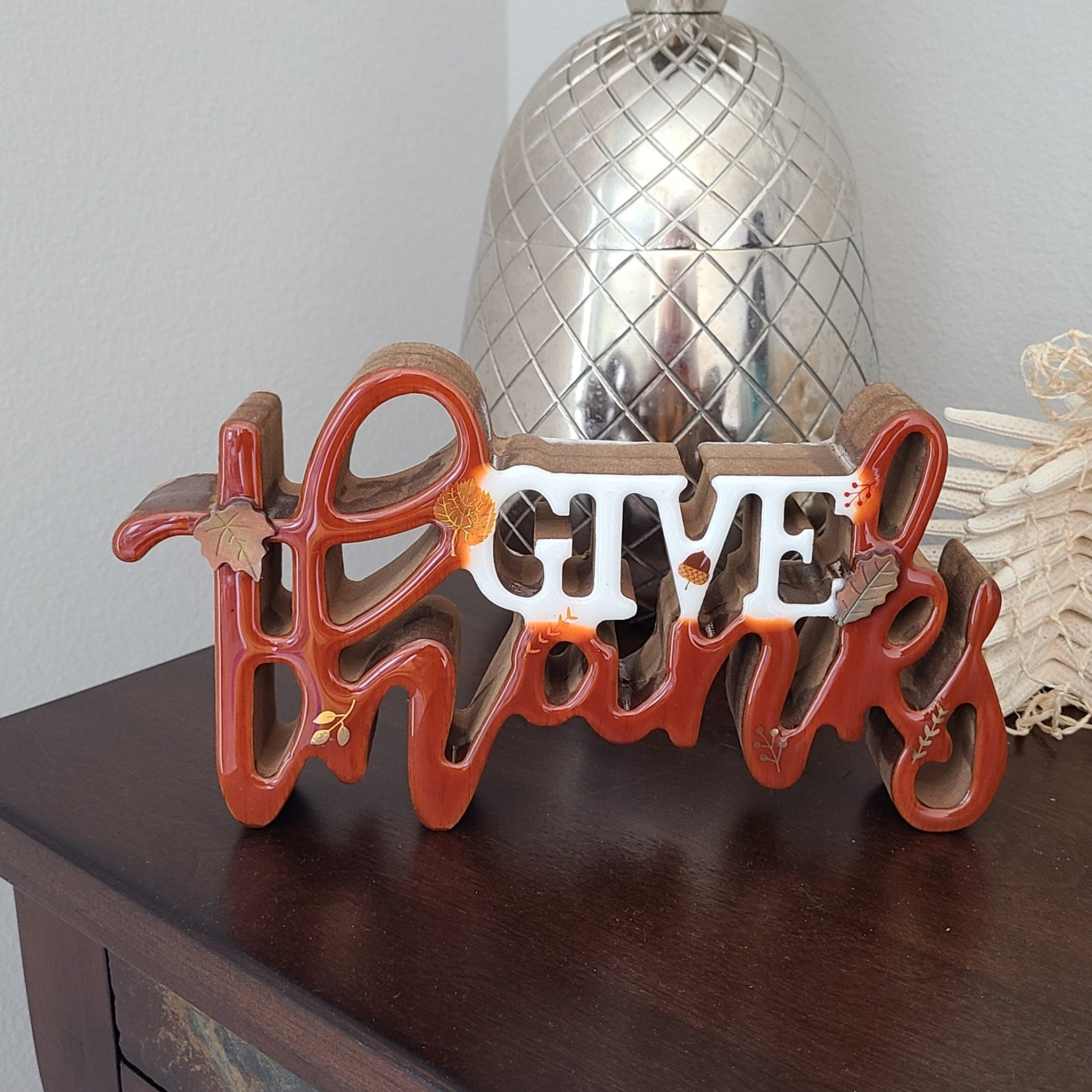 Beautiful Fall decor for your home. 3-D sign says Give Thanks.  Resin on wood (MDF).  Fall leaves, berries and acorn decals and two resin leaves add to the white and umber sign.  Can sit on a table or shelf or could be hung on the wall.  Approximate size: 10 inches long; 5.5 inches tall and 1.5 inches wide