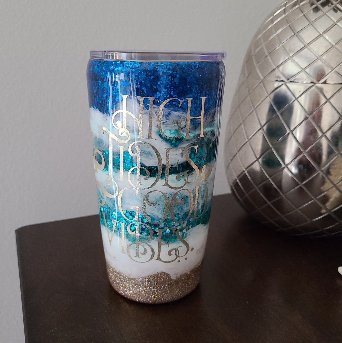 Beautiful water sparkling through big waves in this tumbler.  High Tides and Good Vibes.  At least two layers of resin over the decal ensure that it will not come off.  Various colors of the ocean sparkle through as the big white waves of the ocean give off good vibes.  20 oz.  Double Wall Stainless Steel under the resin.  Comes with lid, Stainless Steel straw and cleaner brush.  Hand Wash only in warm water. DO NOT put in the dishwasher.