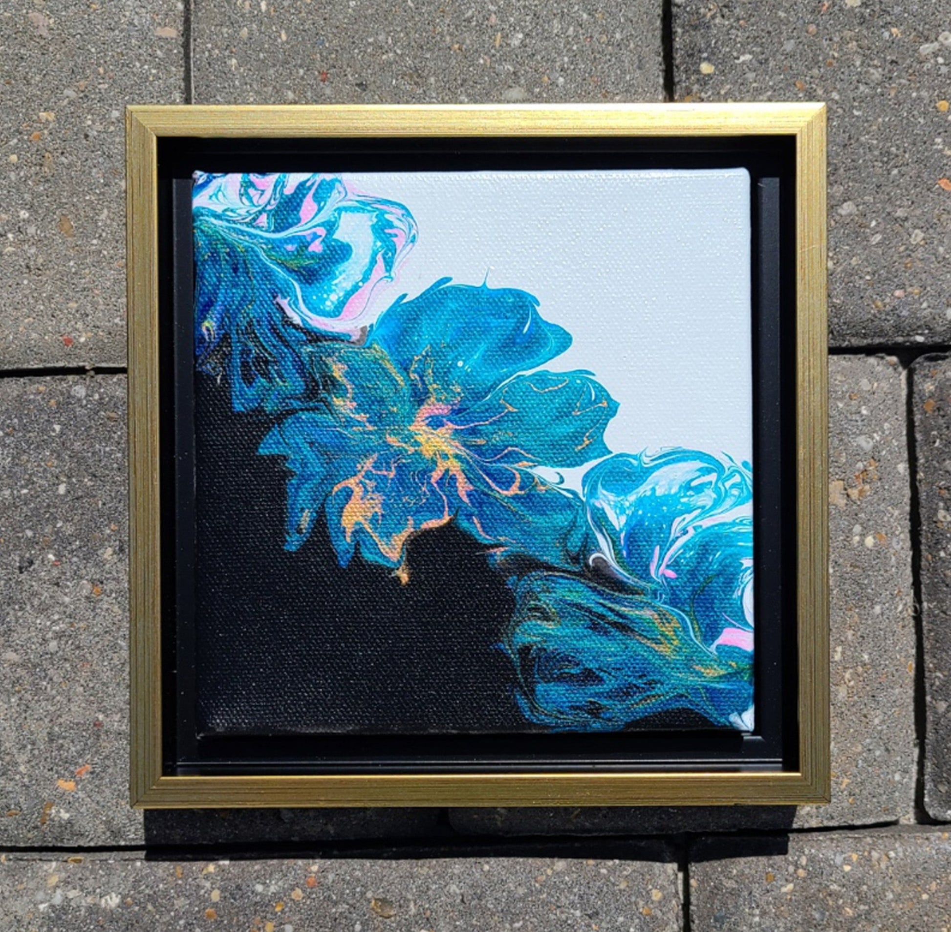 Small piece of art with big impact!  The canvas is 6 x 6 in a floater frame.  Artwork can hang or sit on a shelf or table.  Artwork has a bi-color black and white background.  The blooms are teal/turquoise, gold and pink.  Floater frame is black and gold.  Approximate overall measurements: 7.25 x 7.25 x 1.25 inches  I can sign on the back if you'd like.