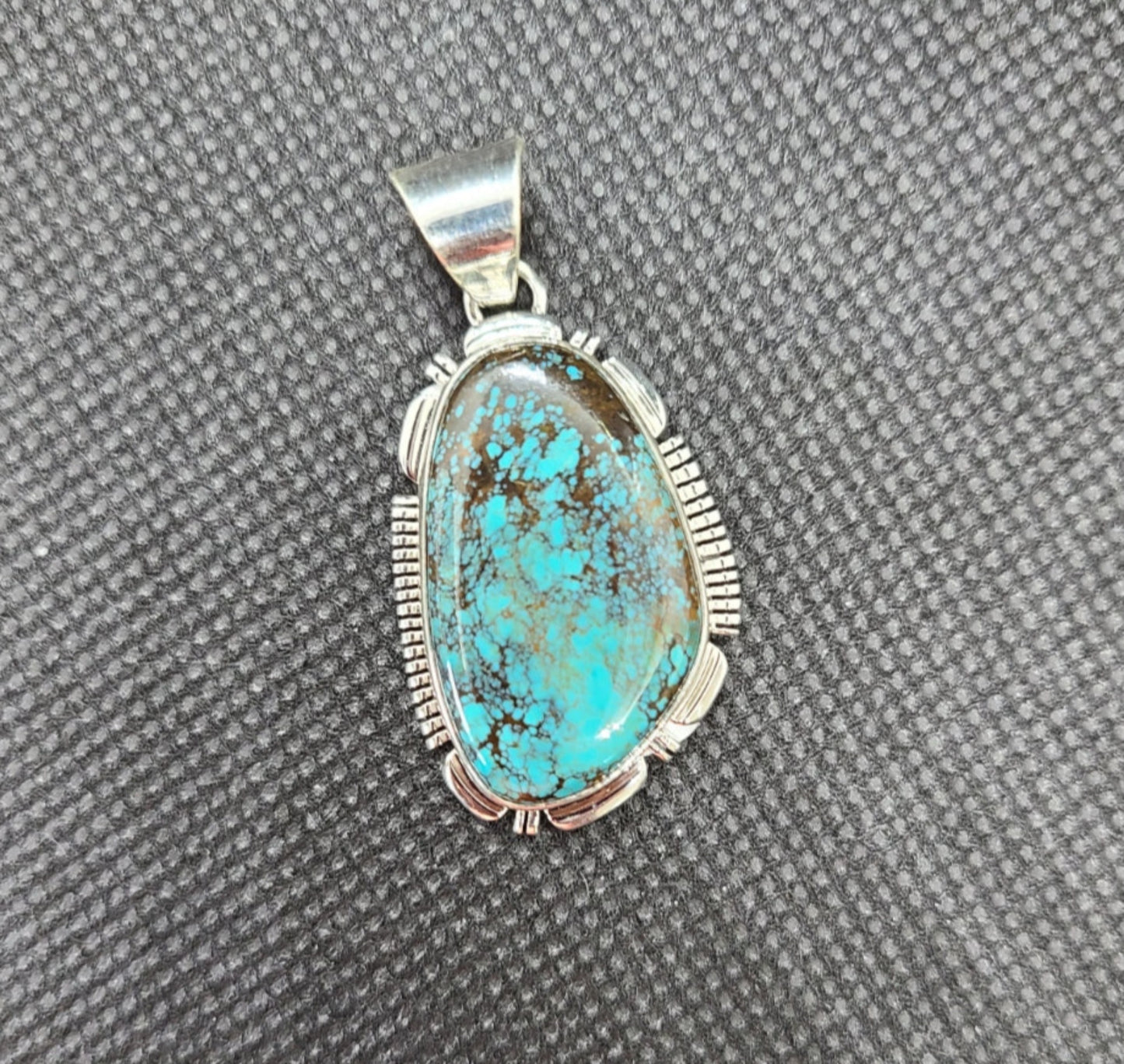 New with tags! Beautiful Bisbee Turquoise pendant by Navajo Artist, Larry M. Yazzie. Bisbee Turquoise is very rare and comes from the Bisbee Mine in Arizona which was closed in 1975.  There is very little Bisbee Turquoise available today and due to it's rarity and exceptional beauty it is very valuable. The stone is set in a Sterling Silver bezel with saw cuts.  The bail is large enough to accommodate most any chain or leather. MSRP: $500  Item will be shipped insured and a Signature will be required.
