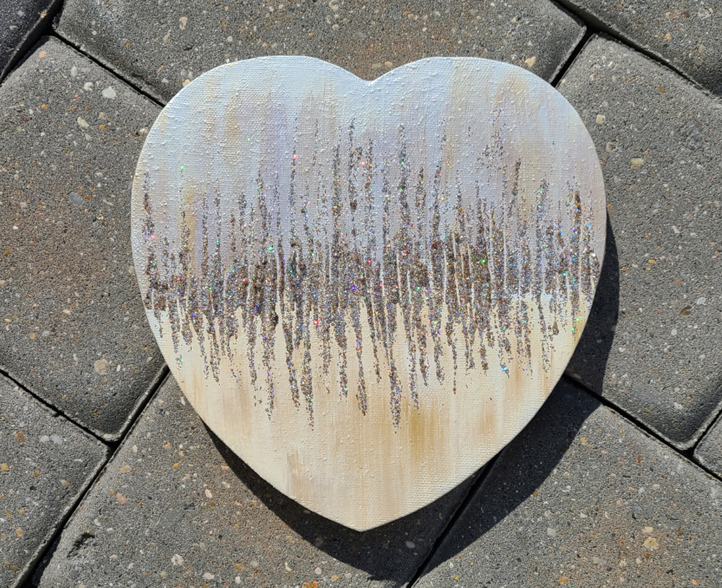 8 inch tall heart shaped canvas.  Painted in a Shabby Chic style, off white with shades of gold and brown overlay.  Center line of various metal tones of glitter are spread up and down for an effect that looks like a fast heartbeat.