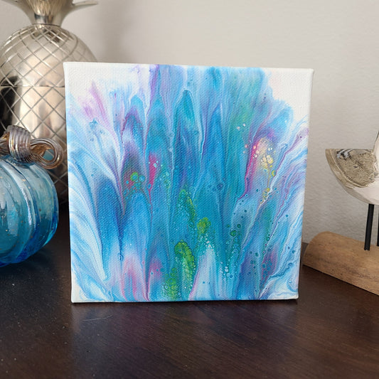 6x6 Canvas, Acrylic art. Fingers of blue, purple and pink with splashes of green and yellow make this abstract art look like Spring is blooming.  Can sit on a shelf or hang on a wall.