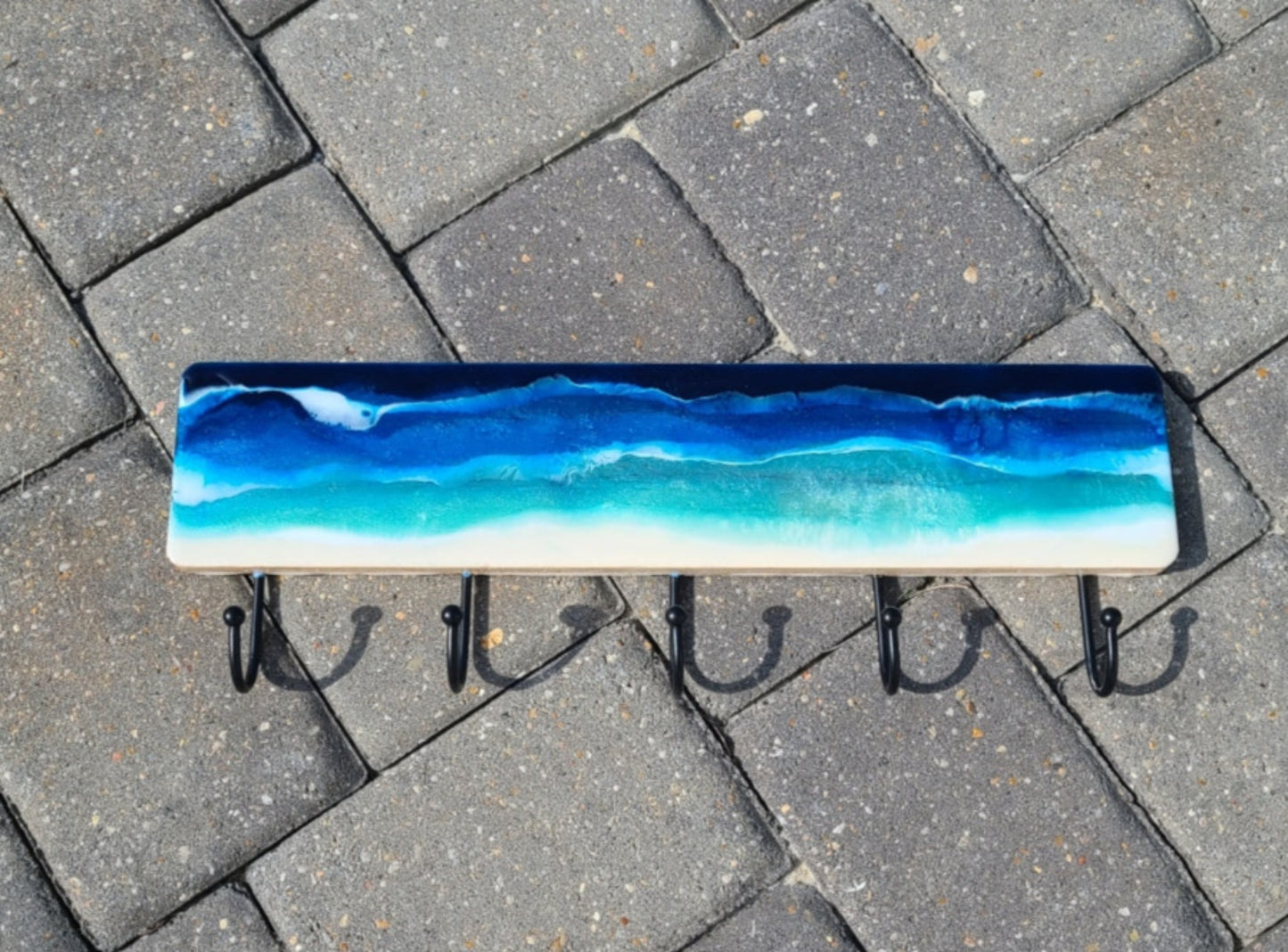 I used resin to create this beach and water scene, lots of sparkle if you look closely.  White waves crash over the colorful water.  Resin is UV resistant.  Metal hooks for hanging towels, kid's clothes, leashes or hats.  Approximate size: Wood: 18 x 4 inches; hooks add another 2.5 inches.  Key Holes on back for hanging.