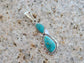 Two stone turquoise pendant. Kingman, AZ turquoise. Navajo artist Sam Yellowhair. Set in Sterling Silver. Small twisted wire around the smaller top stone and twisted wire around the larger bottom stone with back-plate that has cut-outs on it. Approximately 2.5 inches long including bail.  Bail is large enough to accommodate most necklaces.